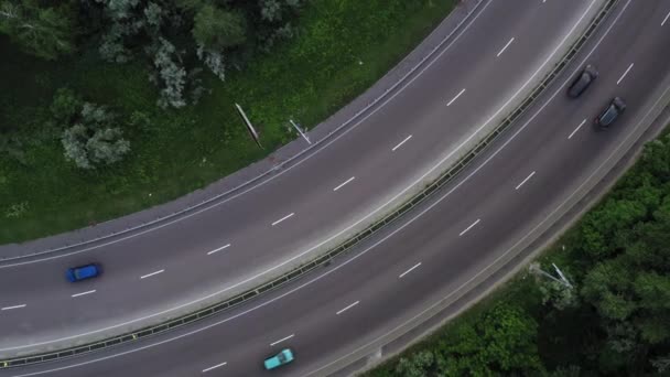 Coches y camiones se mueven a lo largo de los carriles de la carretera entre el follaje verde - Rocket drone shot — Vídeo de stock