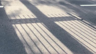 Sabahın erken saatlerinde asfalttaki çitlerin gölgeleri - üretim için kaplama ya da arkaplan.
