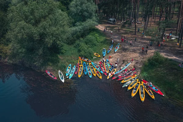 Many tourist kayaks on the river bank on the edge of the forest - camp during kayaking on the river