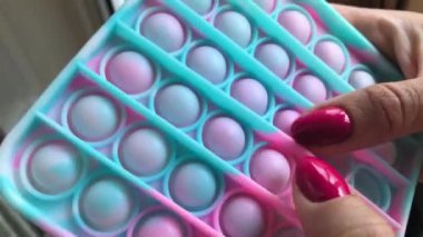 Kadın silikon oyuncak Pop It oynuyor: zihinsel sağlığı geri getirmek için parmaklarıyla kabarcıklara bastırıyor