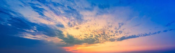 Magnifiche nuvole arancio-lilla al tramonto. Un lampo di sole nel cielo blu del tramonto. — Foto Stock