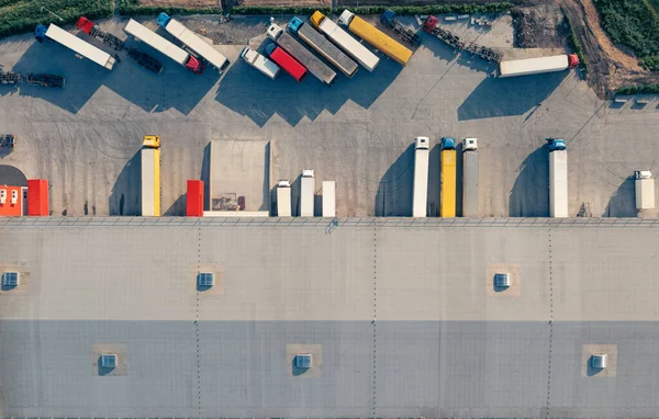 Nákladní automobily jsou naloženy a vyloženy v nákladovém terminálu - letecký top vu drone shot. — Stock fotografie