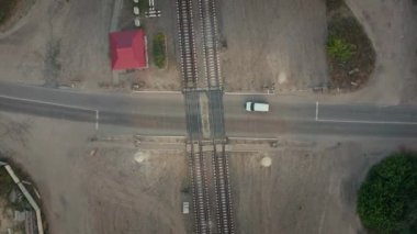 Seviye geçişleri: en üst hava aracı görüntüsü. Beyaz araba rayları geçiyor..