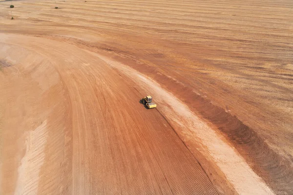 Rolling the soil base with a roller to prepare the basis soil for laying asphalt — 图库照片