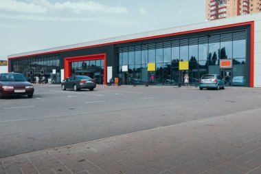 Dışarıdaki süpermarkette araba parkı ve cam vitrin var.