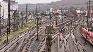 WURZBURG, GERMANY - JULY 15, 2025: elevated view of a passenger train likely a Deutsche Bahn service navigating a busy railway station area with multiple tracks and urban buildings on a cloudy day