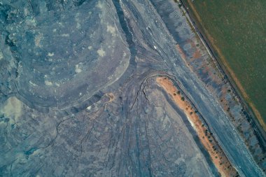 Büyük bir endüstriyel hurda yığını ya da kuyruk göletinin yukarıdan aşağıya hava görüntüsü. Soyut jeomorfik desenler toksik mavi-gri renkler, çatlaklar ve ciddi çevresel hasarlar gösteriyor..