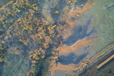 İnsansız hava aracı, kıvrımlı bir nehrin üzerinde güzel bir günbatımını yakalıyor. Barışçıl manzara, sol yakadaki yıkılmış binaların yıkıntılarıyla şiddetle çelişiyor, savaşın gerçekliğini gözler önüne seriyor..