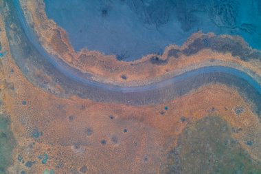 Endüstriyel mavi atığı topçu patlamalarıyla yaralanmış kuru bir alandan ayıran bir savaş bölgesindeki yılandan insansız hava aracı atışı. Savaş yıkımına, bomba kraterlerine ve zehirli kirliliğe tepeden bakan bir bakış açısı. Ukrayna 'da Ecocide.