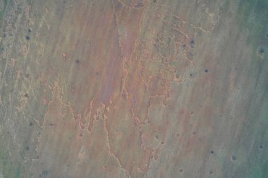 Zehirli bir alan yüzeyinde kırmızı, yeşil, kahverengi ve yeşil karışımlı mineral çizgilerinin havadan drone görüntüsü. Endüstriyel atık akışının yukarıdan görünüşü soyut bir sıvı dokusu yaratıyor. Madencilik kirliliği geçmişi.