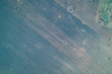 Ağır topçu ateşinden kaynaklanan mermi delikleriyle kaplı yaralı bir tarla manzarası. Bu yatay dron fotoğrafçılığı, Rus işgalinin çevresel etkisini ve NATO ve Avrupa ülkeleri üzerindeki güvenlik krizini göstermektedir..