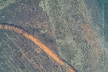 Turuncu kil setleri olan eğri büğrü bir tanksavar siperinin yukarıdan aşağıya havadan görünüşü sıralanmış beton ejderhaların diş piramitlerine paraleldir. Bu sahne zırhlı araçları durdurmak için tasarlanmış güçlendirilmiş bir savunma hattını gösteriyor..