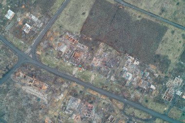 Her tarafı yanmış temeller ve yıkılmış evlerin yıkıntılarıyla çevrili hayalet bir kasabadaki yol kesişiminin havadan görüntüsü. Issız arazi, şiddetli çatışmanın ve tüm mal kaybının kesin bir kanıtı olarak hizmet vermektedir..