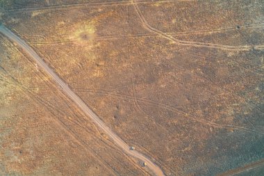 Dokulu tarımsal alanlardan geçen toprak bir yolun yukarıdan aşağı havadan görünüşü. Bu asfaltsız yol, Doğu Avrupa 'nın aktif savaş bölgesinde askeri lojistik ve ulaşım için kritik bir yol görevi görüyor..
