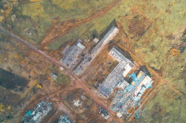 Savaştan kaynaklanan hasarı gösteren uzun tarımsal depolama hangarlarının tepeden tırnağa insansız hava aracı görüntüsü. Yapılar, tarım arazisindeki kırsal bir toprak yolun yanında yer alıyor..