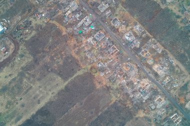 Çatısız evler ve molozların savaş tahribatının boyutlarını gösterdiği yıkık bir yerleşim bölgesinin tepeden aşağı havadan görüntüsü. Sahne, askeri çatışma ve sivil bir bölgedeki bombardımanın trajik sonuçlarını çekiyor..