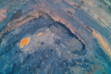 Zehirli toprak ve turuncu kimyasal birikintileri olan kıvrımlı maden terası. Yüksek çözünürlüklü endüstriyel kirlilik ve tehlikeli atık dokusu, fotokopi alanı ile yatay üst görünüm drone görüntüsü.