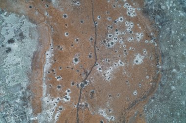 Eğri bir derenin havadan görünüşü ya da kurumuş bitkilerle dolu bir çayırı kesen bir hendek. Manzara eşsiz bir C-şekli ya da U-dönüşü deseni oluşturur, minimalist bir doğal tasarım yaratır..