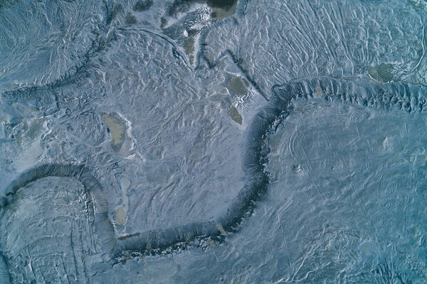 Aerial top-down view of wet industrial sludge creating a textured grey surface. The muddy ash and toxic waste pattern resembles wet cement, clay soil, or a desolate lunar landscape, symbolizing environmental pollution and industry.