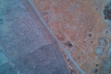 Karmaşık beyaz buz kristallerinin havadan görünüşü koyu donmuş toprakta tüylü bir desen oluşturuyor. Bu yüksek kontrastlı kış dokusu soyut arka planlar, mevsimlik tasarımlar ve bilim temaları için idealdir..