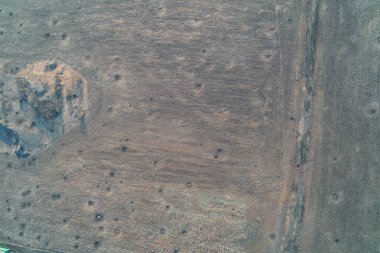 Yukarıdan aşağıya kuru, kabataslak zemin dokusu, sayısız çukurları ve düz olmayan yüzeyi var. Kuraklığı, erozyonu, çorak araziyi ya da Mars yüzeyini temsil eden soyut kahverengi toprak arka planı.