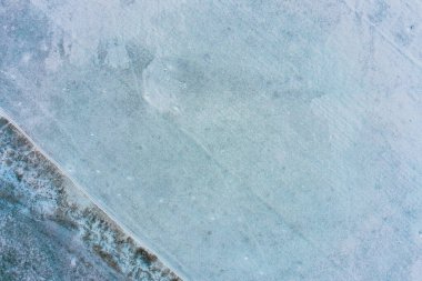 Karlı zemindeki solmuş bitki örtüsünün ritmik düzeni yapılandırılmış doğal bir şablon yaratır. Bu görüntü, kışın derinliklerinde pasif kalmış bir tarım alanının dokusunu yakalar..