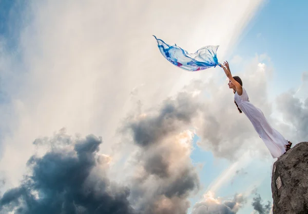 Güzel kız bir beyaz elbise duran kayanın üzerinde