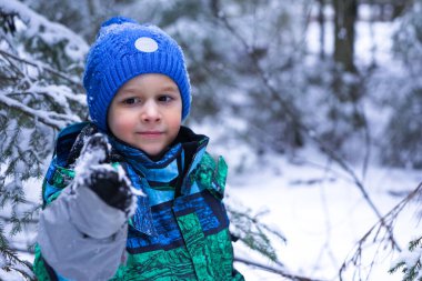 A small happy boy in winter forest