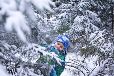 A small happy boy in winter forest