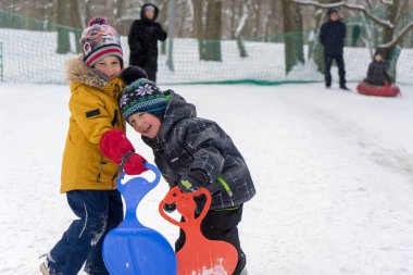 İki küçük çocuk karla oynuyor.