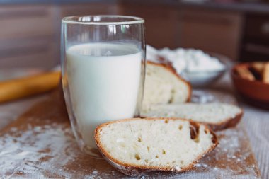 Mutfaktaki bir tahtanın üzerinde süt ve kurabiyeyle kokulu ve çıtır çıtır ekmek. Ev yapımı taze ekmek. Yuvarlak ev yapımı ekmek..