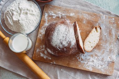 Mutfaktaki bir tahtanın üzerinde süt ve kurabiyeyle kokulu ve çıtır çıtır ekmek. Ev yapımı taze ekmek. Yuvarlak ev yapımı ekmek..