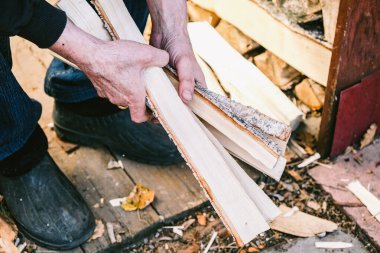 Köy. Balta ile odun kes. Soba için yakacak odun. Bir adamın ellerinde yakacak odun.