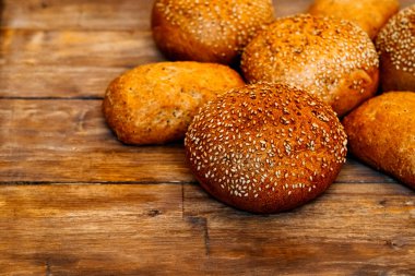 Hamburger, sandviç, susamlı çörek, çörek. Tahta arka planda susam tohumlu taze hamburger ekmeği. Lezzetli hamburger çörekleri.