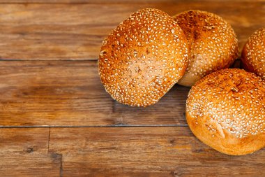 Hamburger, sandviç, susamlı çörek, çörek. Tahta arka planda susam tohumlu taze hamburger ekmeği. Lezzetli hamburger çörekleri.