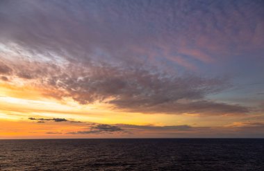 Karayip Denizi 'nin tropikal sularında sürüklenen günbatımı ve dramatik bulut kümeleri gün ışığının son anlarıyla aydınlanır..