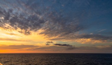 Karayip Denizi 'nin tropikal sularında sürüklenen günbatımı ve dramatik bulut kümeleri gün ışığının son anlarıyla aydınlanır..