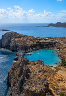 St. Paul Körfezi manzaralı, Yunanistan 'ın Rodos kentindeki Lindos' ta turkuaz su, engebeli uçurumlar ve parlak Akdeniz semaları altında huzurlu bir kıyı manzarası bulunuyor.