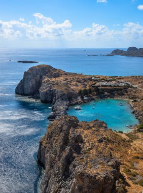St. Paul Körfezi manzaralı, Yunanistan 'ın Rodos kentindeki Lindos' ta turkuaz su, engebeli uçurumlar ve parlak Akdeniz semaları altında huzurlu bir kıyı manzarası bulunuyor.