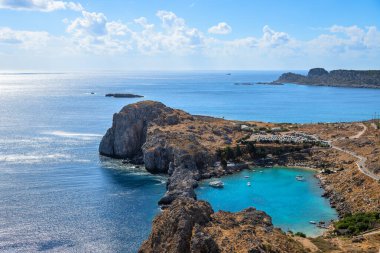 St. Paul Körfezi manzaralı, Yunanistan 'ın Rodos kentindeki Lindos' ta turkuaz su, engebeli uçurumlar ve parlak Akdeniz semaları altında huzurlu bir kıyı manzarası bulunuyor.