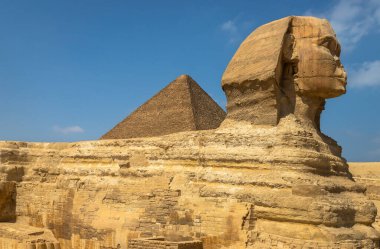 Büyük Giza Sfenksi 'nin arka planda piramit olan yatay görüntüsü, Mısır. Mısır medeniyetinin, tarihinin ve arkeolojisinin simgesi olan en ikonik antik anıtlardan biri.