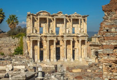 Türkiye 'nin Efes kentindeki Celsus Kütüphanesi' nin ön görüntüsü. Süslü sütunları ve açık mavi gökyüzü altında tarihi mimarisi olan ikonik Roma kalıntıları, popüler arkeolojik simgeler