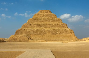 Saqqara 'daki Firavun Djoser' in tarihi Adım Piramidi. Dünyanın en eski anıtsal taş binası ve çöl kumlarıyla mavi gökyüzünün altındaki ilk Mısır piramidi.