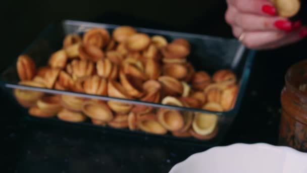 Женщина на кухне готовит домашнее печенье с сгущенным молоком и орехами — стоковое видео