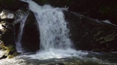 Kayalar ve ağaçlar arasındaki dağ şelalesi