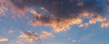 Gün sonunda gökyüzünde bulutlar, altın güneş ışığı titreşimlerde yansıyor.