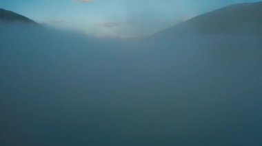 Drone güneşe doğru uçuyor. Sabah güneşi dağlarda, arka planda karla