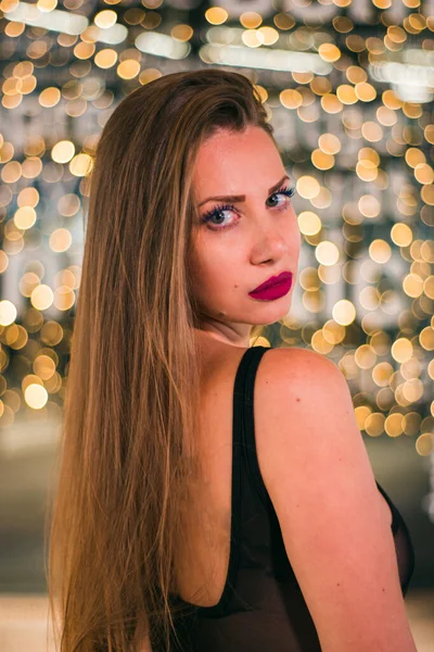 Açık tenli, sarı saçlı, siyah elbiseli, odaklanmamış ışıklı genç bir kadınla Noel fotoğrafı..