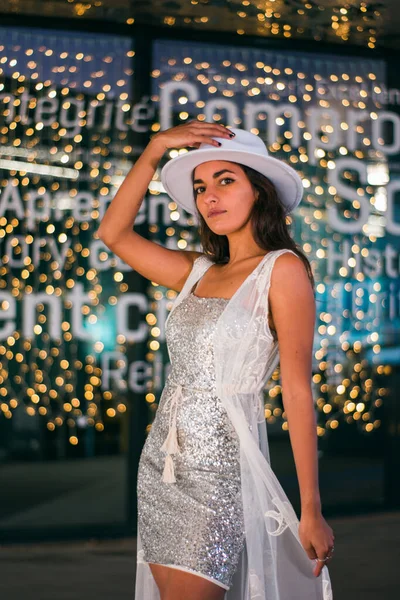 Kahverengi tenli, siyah saçlı, beyaz elbiseli, odaklanmamış ışıklı bir kadınla Noel fotoğrafı..