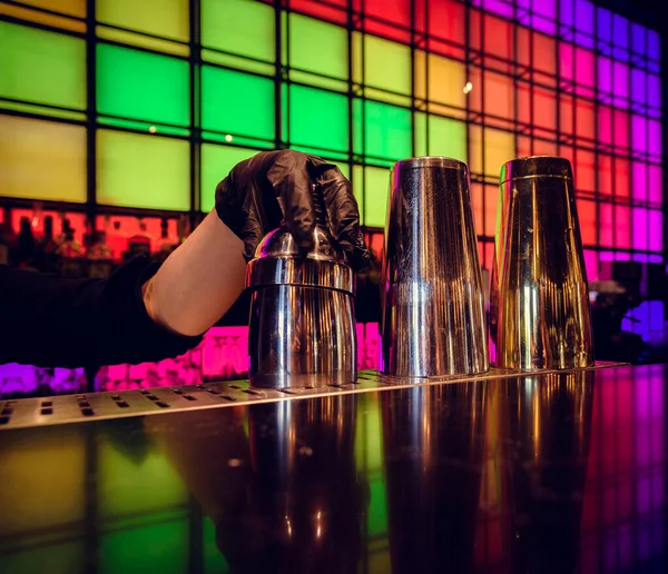 Hand of bartender with shaker on bar counter background